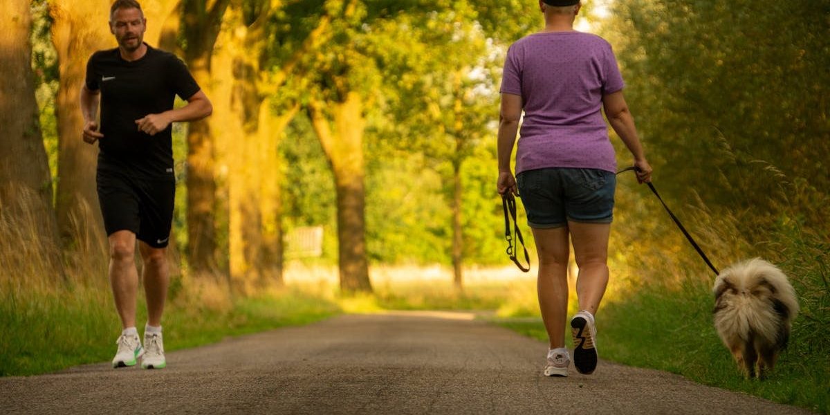 Man jogging and woman walking a dog on a picturesque outdoor path.