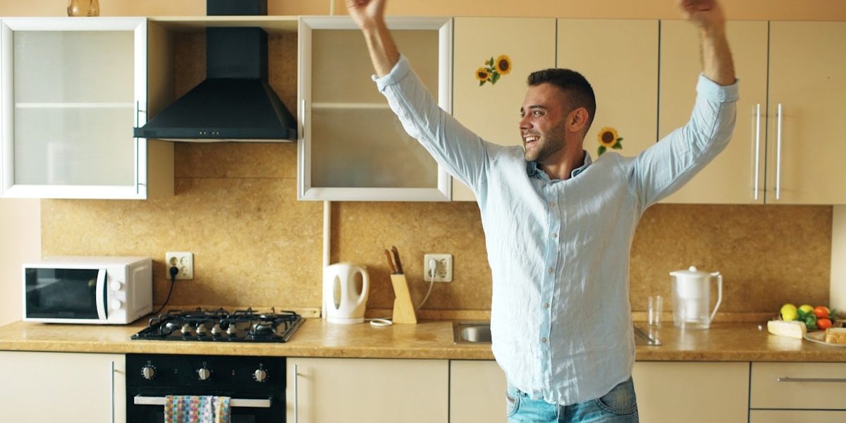 Handsome young funny man dancing in kitchen at home in the morning and have fun on vacation