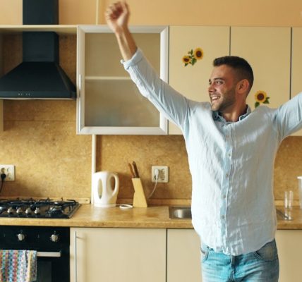 Handsome young funny man dancing in kitchen at home in the morning and have fun on vacation