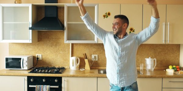Handsome young funny man dancing in kitchen at home in the morning and have fun on vacation