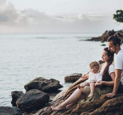 A serene family moment by the seaside, capturing love and relaxation at sunset.