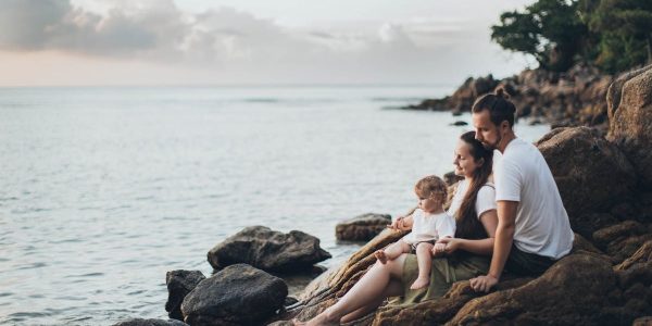 A serene family moment by the seaside, capturing love and relaxation at sunset.