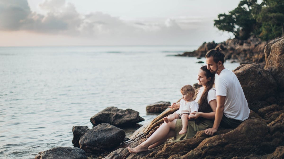 A serene family moment by the seaside, capturing love and relaxation at sunset.